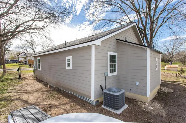 a view of a house with a yard covered with snow and large trees