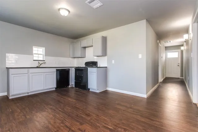 a kitchen with stainless steel appliances granite countertop a refrigerator a sink dishwasher and white cabinets with wooden floor