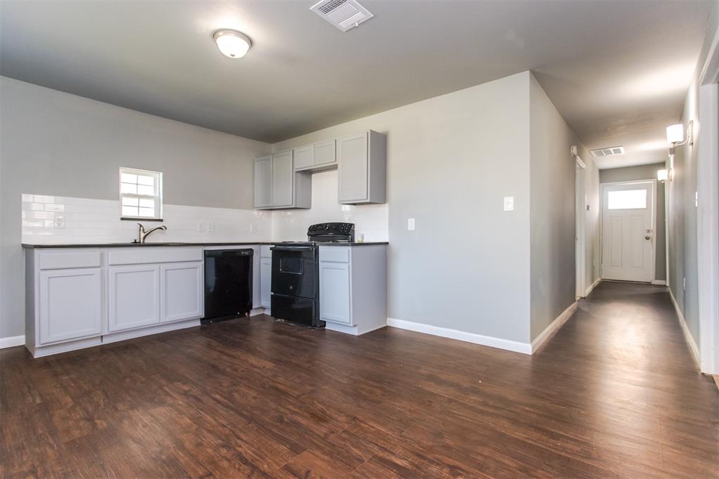 300 South 3rd Street Bonham, TX 75418 - Photo 9 of 14 a kitchen with stainless steel appliances granite countertop a refrigerator a sink dishwasher and white cabinets with wooden floor