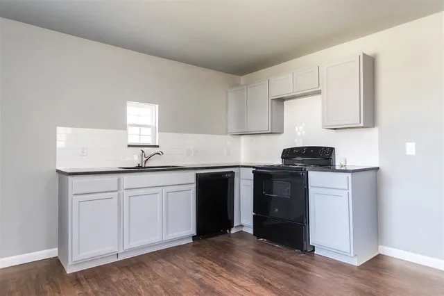 a kitchen with granite countertop white cabinets and black appliances