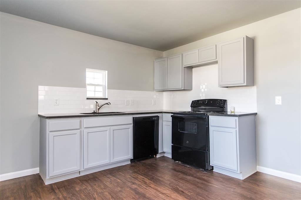 300 South 3rd Street Bonham, TX 75418 - Photo 10 of 14 a kitchen with granite countertop white cabinets and black appliances