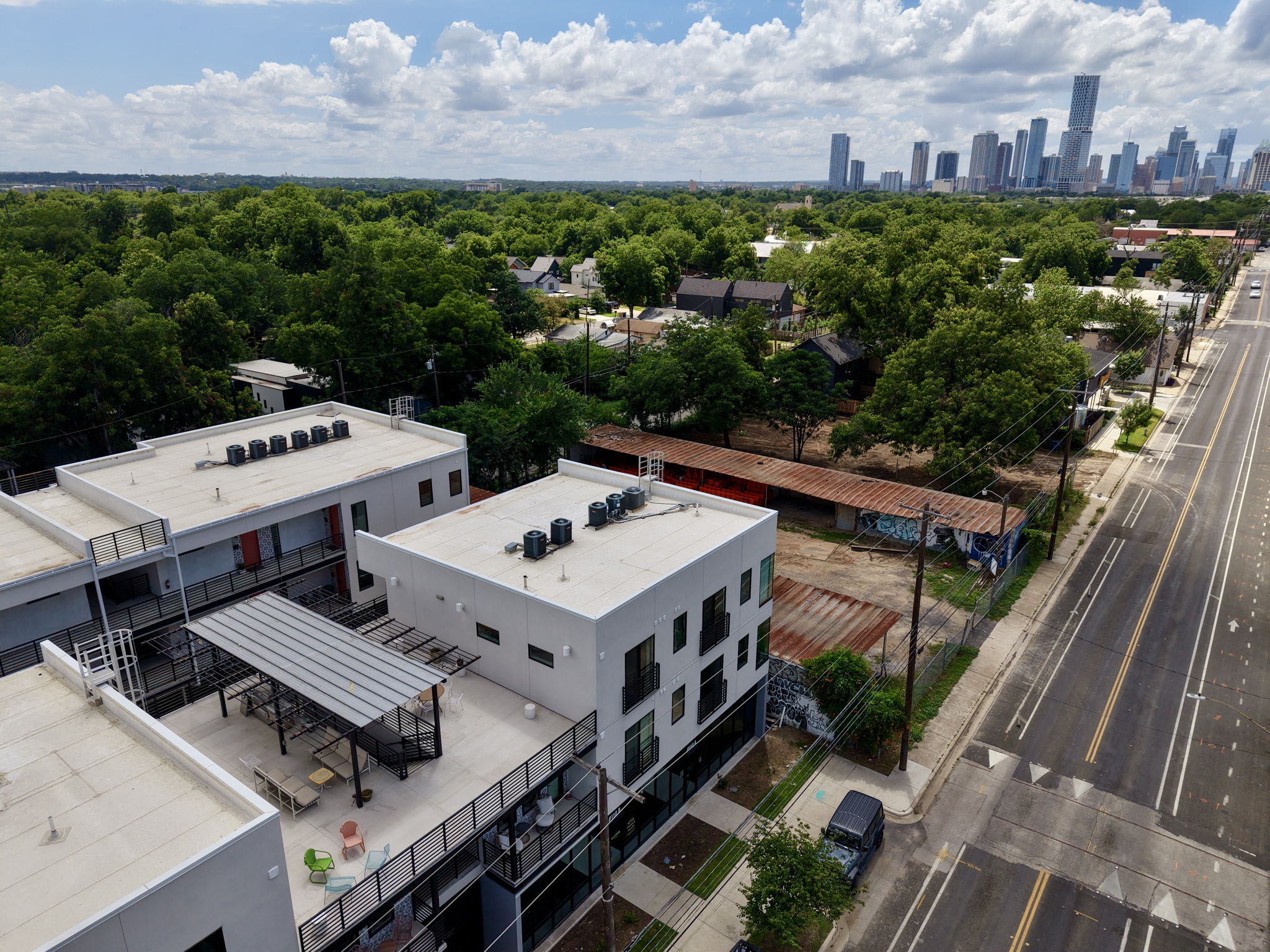 2709 East 5th Street, Unit 1306 Austin, TX 78702 - Photo 24 of 28 An aerial perspective reveals contemporary urban living alongside a tree-lined street and city skyline.