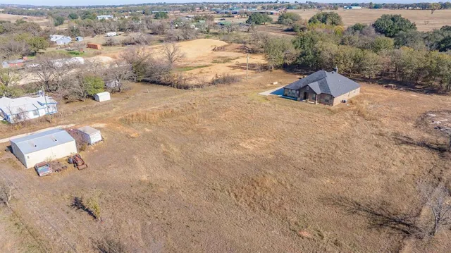 an aerial view of a house with yard and mountain view in back