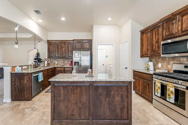 a kitchen with stainless steel appliances granite countertop a sink stove and refrigerator