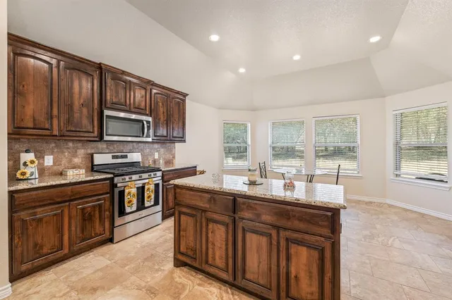 a kitchen with stainless steel appliances granite countertop wooden cabinets a stove top oven a sink and dishwasher