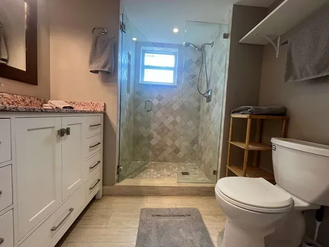 a bathroom with a granite countertop toilet a sink and shower