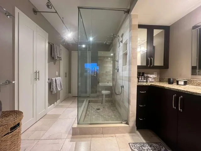 a bathroom with a glass shower door a sink and a mirror