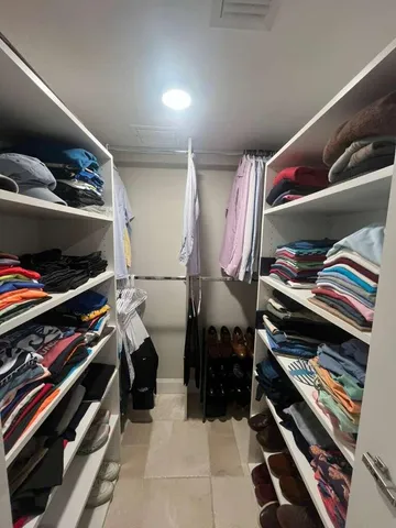 a view of walk in closet with clothes and shoes