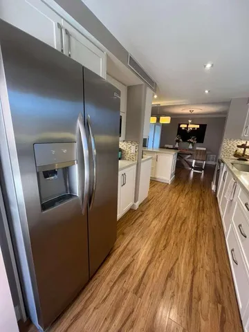 a kitchen with stainless steel appliances granite countertop a refrigerator a stove and a wooden floors