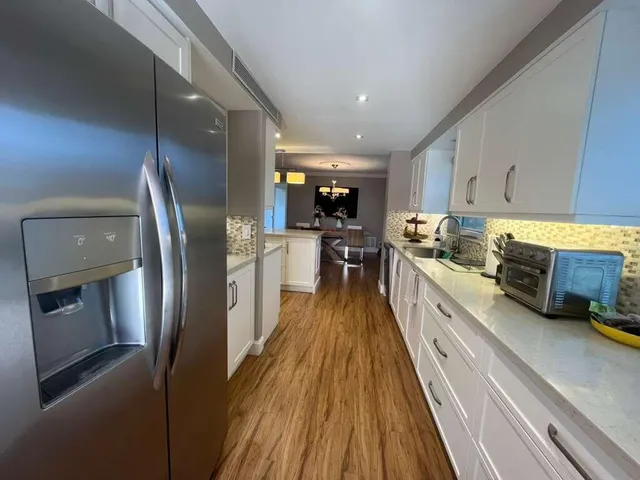 a kitchen with stainless steel appliances granite countertop a refrigerator a stove and a sink with wooden floor