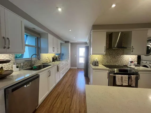 a large kitchen with stainless steel appliances granite countertop a stove a sink dishwasher and a refrigerator