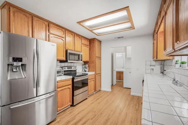 a kitchen with stainless steel appliances a refrigerator a stove top oven a sink and cabinets