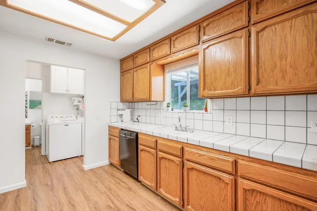 a kitchen with stainless steel appliances granite countertop a sink cabinets and wooden floor
