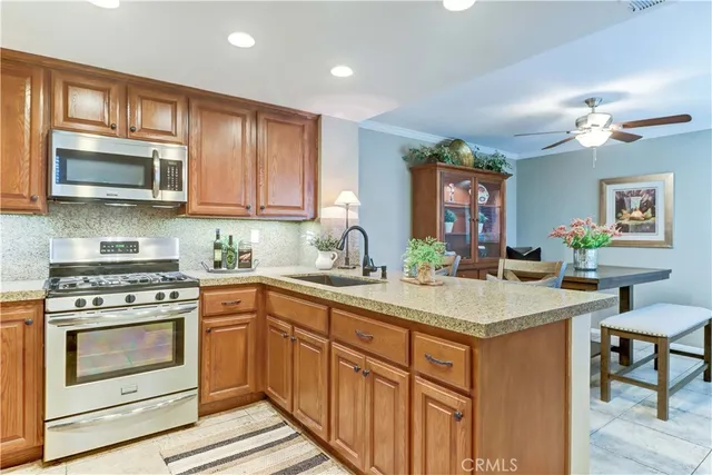 a kitchen with stainless steel appliances granite countertop a stove a sink dishwasher and a microwave oven with wooden cabinets