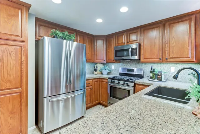 a kitchen with stainless steel appliances granite countertop a refrigerator stove microwave and sink