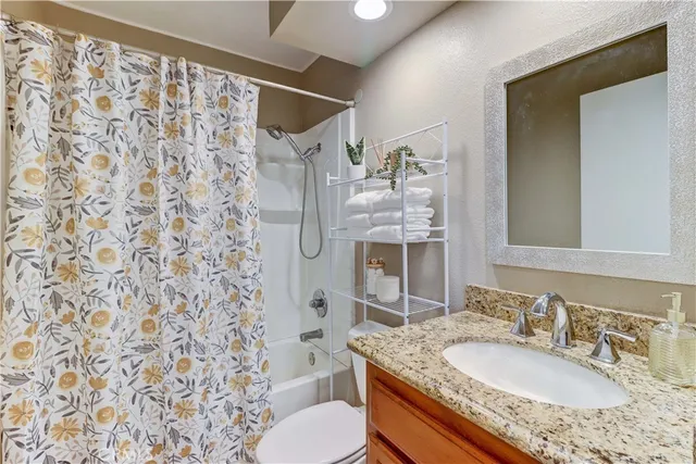 a bathroom with a granite countertop sink a toilet and a mirror