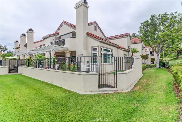 a view of a house with a small yard and large trees