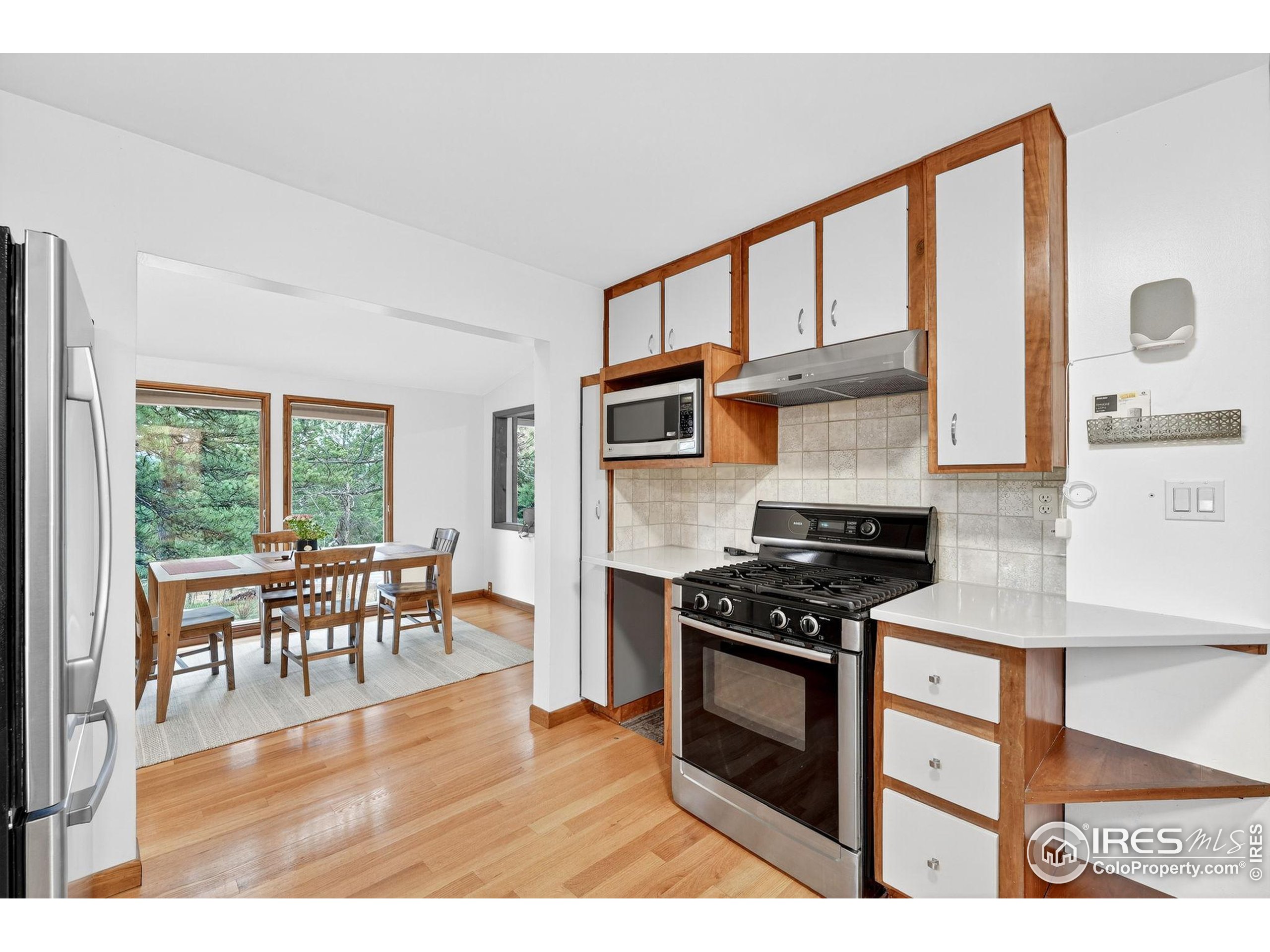 1707 Ridge Road Nederland, CO 80466 - Photo 21 of 50 a kitchen with stainless steel appliances granite countertop a stove top oven a sink a dining table and chairs with wooden floor