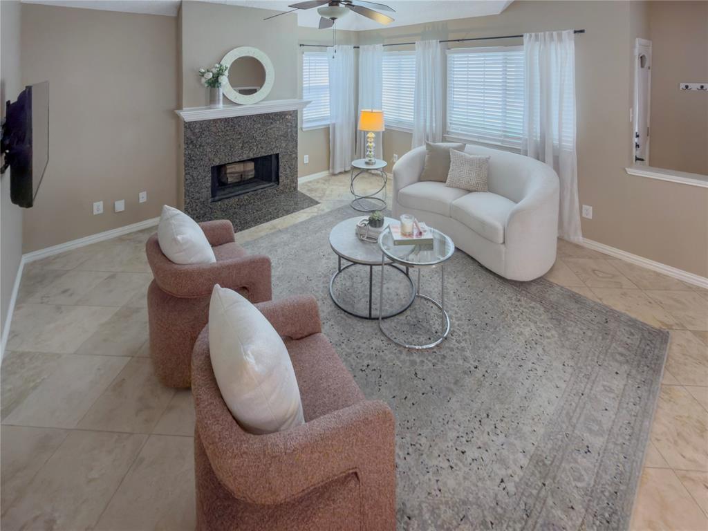 4234 Timberglen Road Dallas, TX 75287 - Photo 4 of 32 Living space featuring a fireplace with a granite surround and hearth, neutral wall paint, tile flooring, and multiple windows with blinds