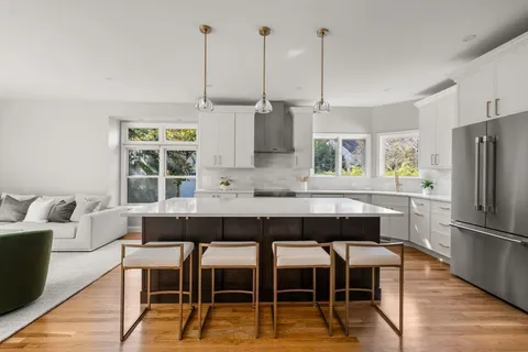 a kitchen with stainless steel appliances kitchen island granite countertop a dining table chairs and granite counter tops