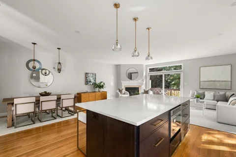 a open kitchen with stainless steel appliances granite countertop a sink a stove and chairs with wooden floor