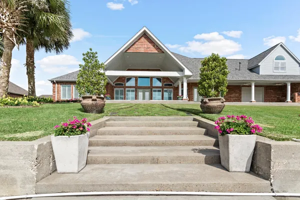a front view of house and yard with beautiful flowers and green space