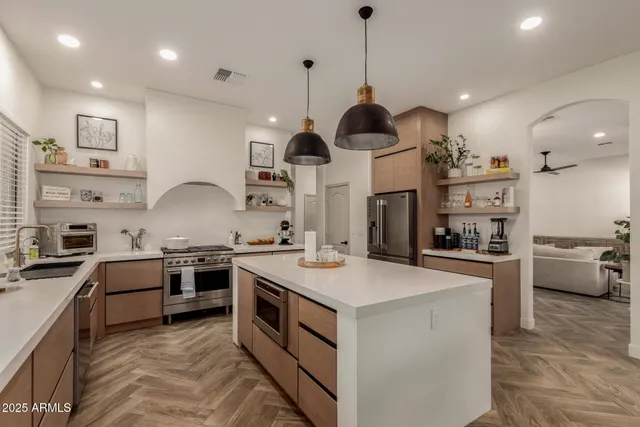 a kitchen with kitchen island a stove a sink a oven and a refrigerator