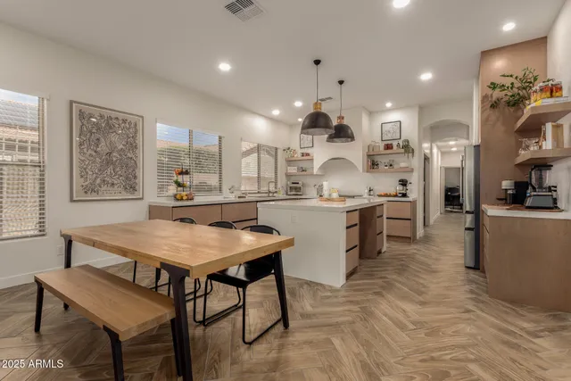a kitchen with stainless steel appliances kitchen island granite countertop a table chairs sink and cabinets