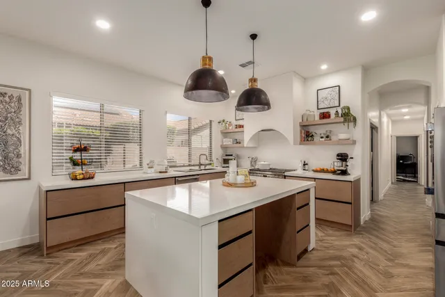 a kitchen with stainless steel appliances granite countertop a sink a stove and a wooden floors