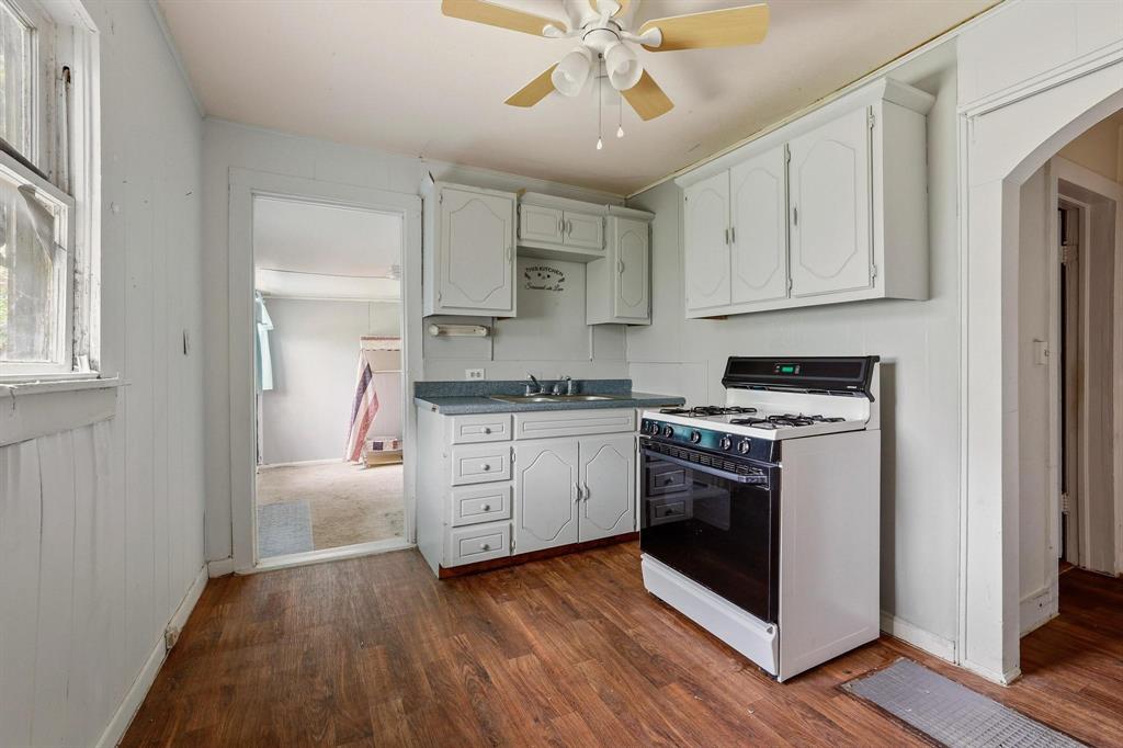 421 East Hull Street Denison, TX 75021 - Photo 16 of 33 a kitchen with stainless steel appliances white cabinets and wooden floor