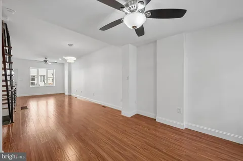 a view of empty room with wooden floor and stairs