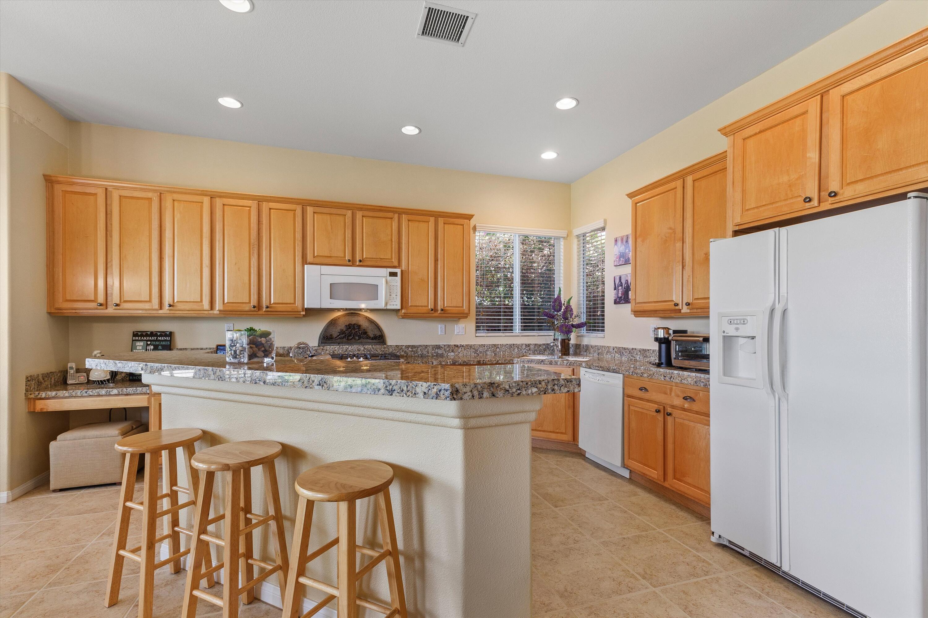 27 Via Del Maricale Rancho Mirage, CA 92270 - Photo 4 of 52 a kitchen with stainless steel appliances granite countertop a stove a refrigerator a sink a stove and white cabinets with wooden floor