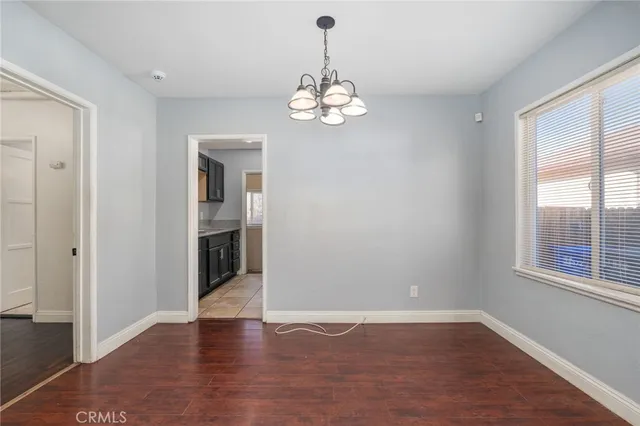 an empty room with wooden floor chandelier and windows