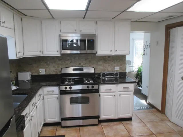 a kitchen with white cabinets and appliances