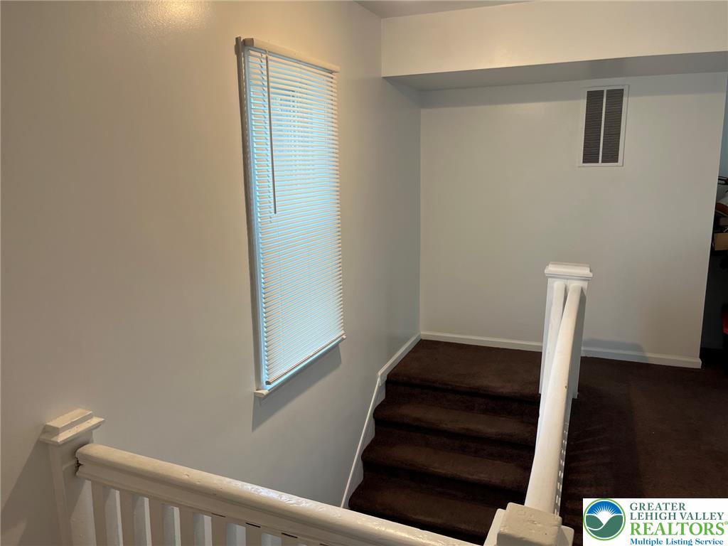 765 3rd Street Whitehall, PA 18052 - Photo 20 of 30 A window with blinds provides natural illumination to the carpeted staircase, creating a well-lit transition space.