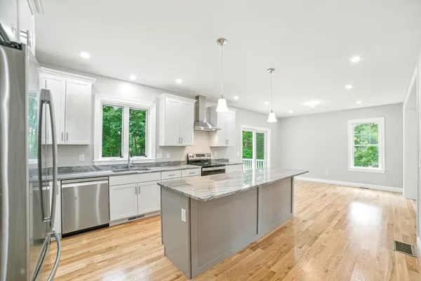 a large kitchen with a large counter top sink stainless steel appliances and cabinets