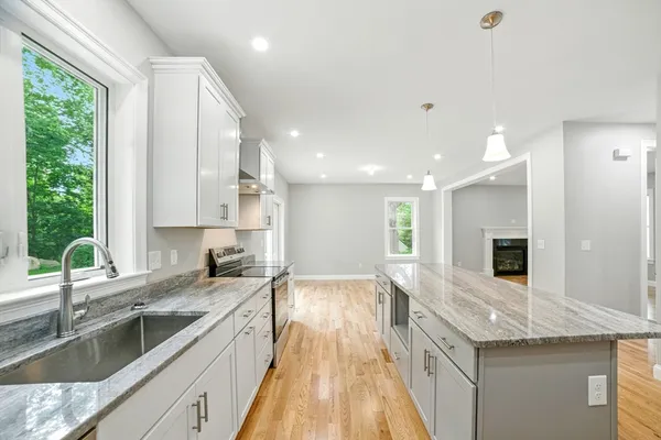 a large kitchen with stainless steel appliances granite countertop a sink stove and refrigerator