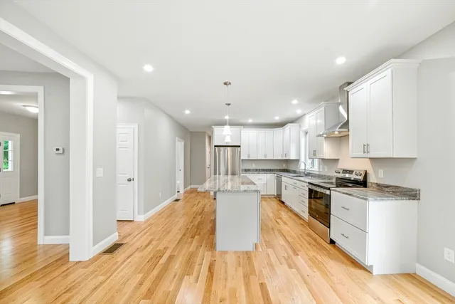 a large kitchen with stainless steel appliances lots of counter space and wooden floor