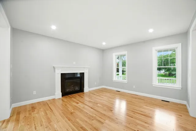 an empty room with windows and fireplace