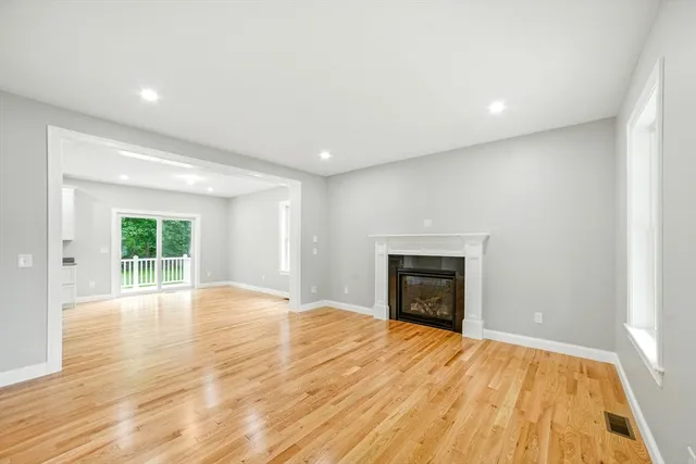 an empty room with wooden floor fireplace and windows