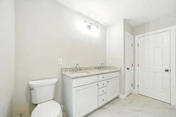 a bathroom with a granite countertop toilet sink and mirror