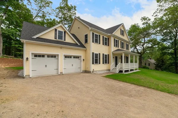 a front view of a house with a garden and trees