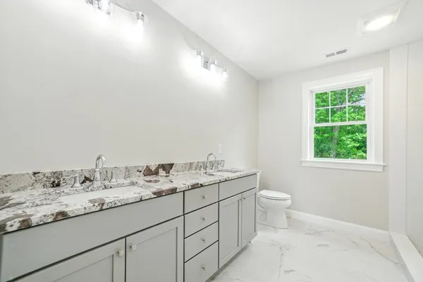 a bathroom with a granite countertop sink a toilet and a mirror
