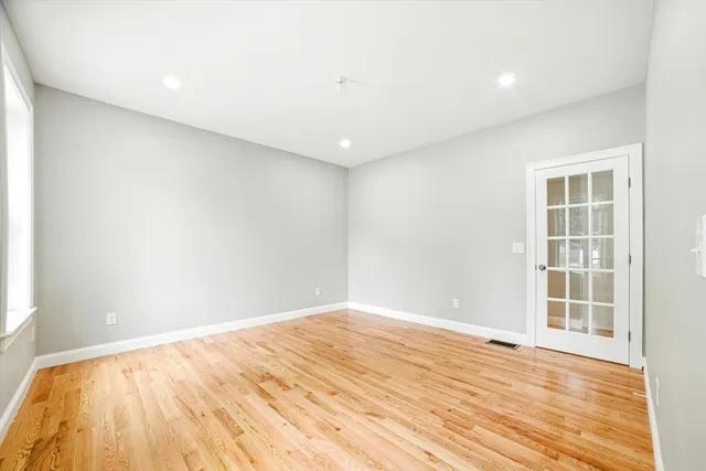 an empty room with wooden floor and windows