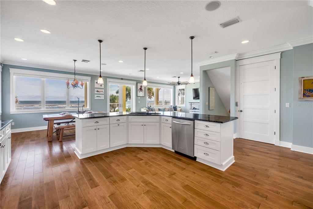 6101 Turtlemound Road New Smyrna Beach, FL 32169 - Photo 12 of 82 a kitchen with stainless steel appliances kitchen island granite countertop a stove a sink and white cabinets with wooden floor