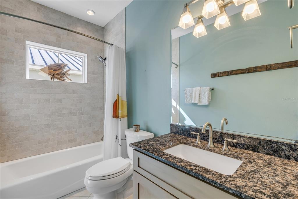 6101 Turtlemound Road New Smyrna Beach, FL 32169 - Photo 42 of 82 a bathroom with a granite countertop toilet a sink and a mirror