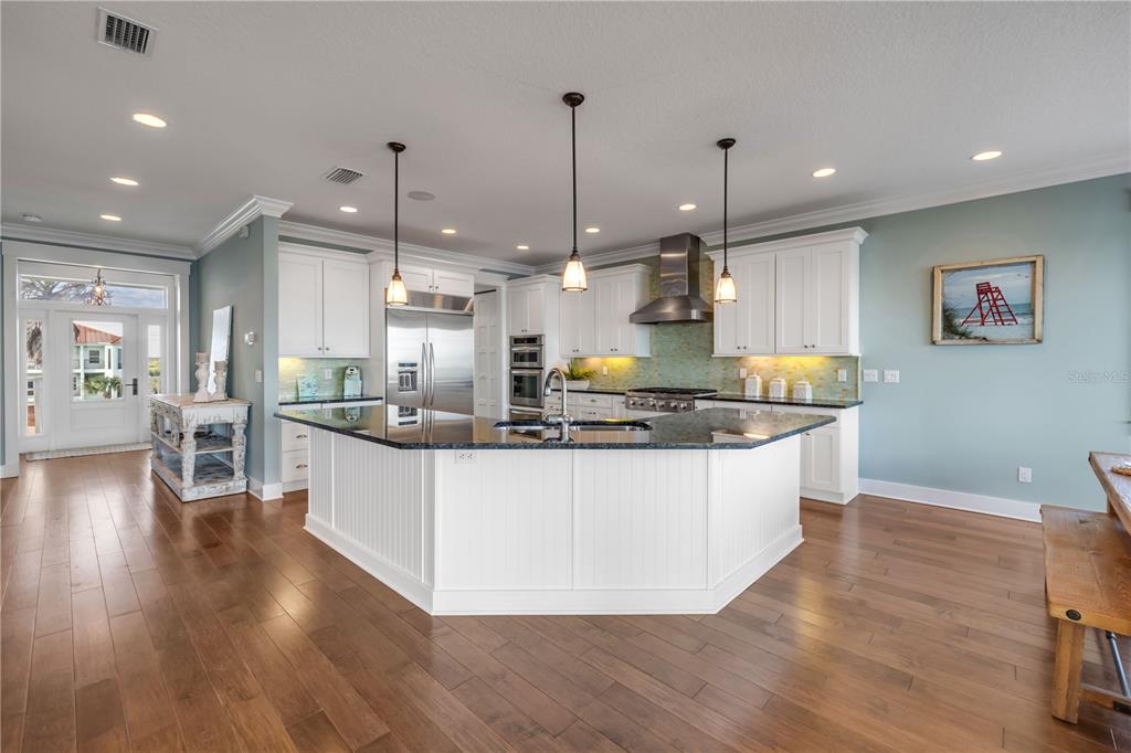 6101 Turtlemound Road New Smyrna Beach, FL 32169 - Photo 10 of 82 a large kitchen with stainless steel appliances granite countertop a stove a sink a refrigerator a center island and a wooden floor