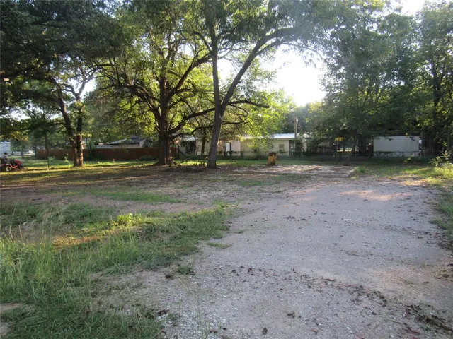 a view of dirt yard with trees