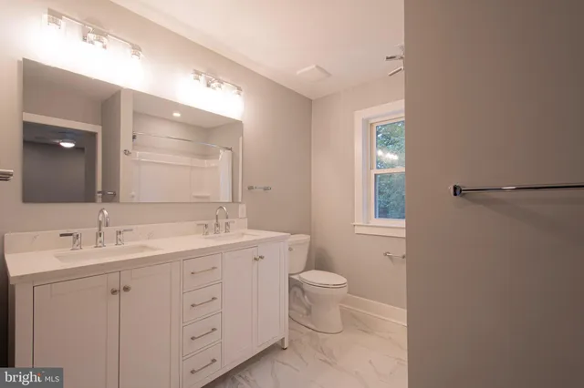 a bathroom with a double vanity sink a toilet and a mirror