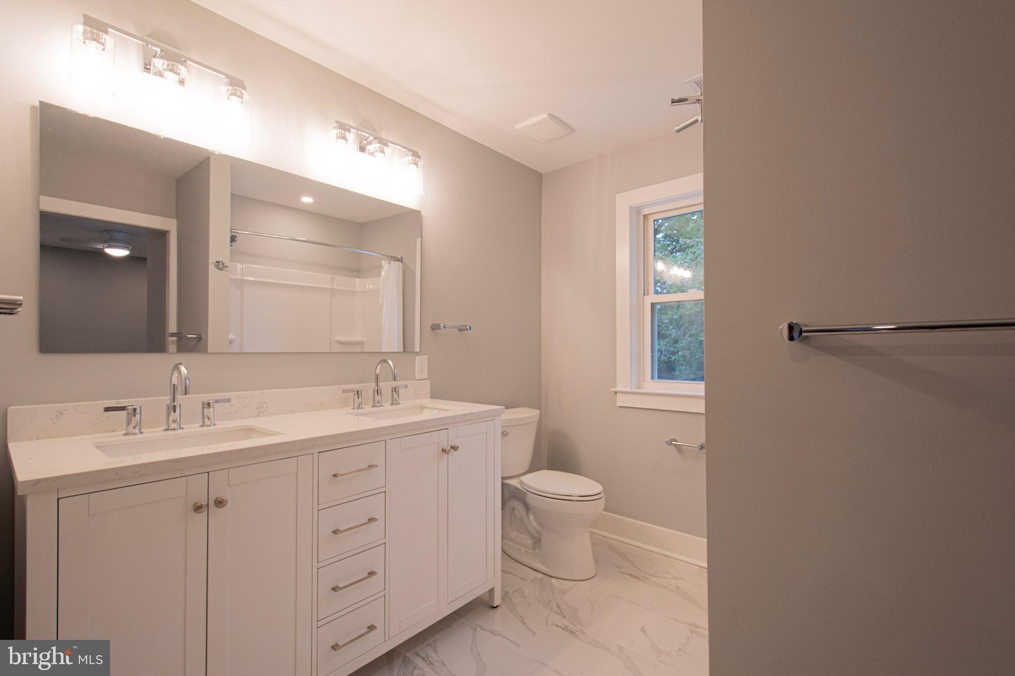 21 Manor Road Paoli, PA 19301 - Photo 12 of 35 a bathroom with a double vanity sink a toilet and a mirror